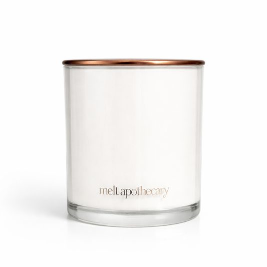 Clear glass candle with a copper lid on a white background, featuring the brand 'melt apothecary'.