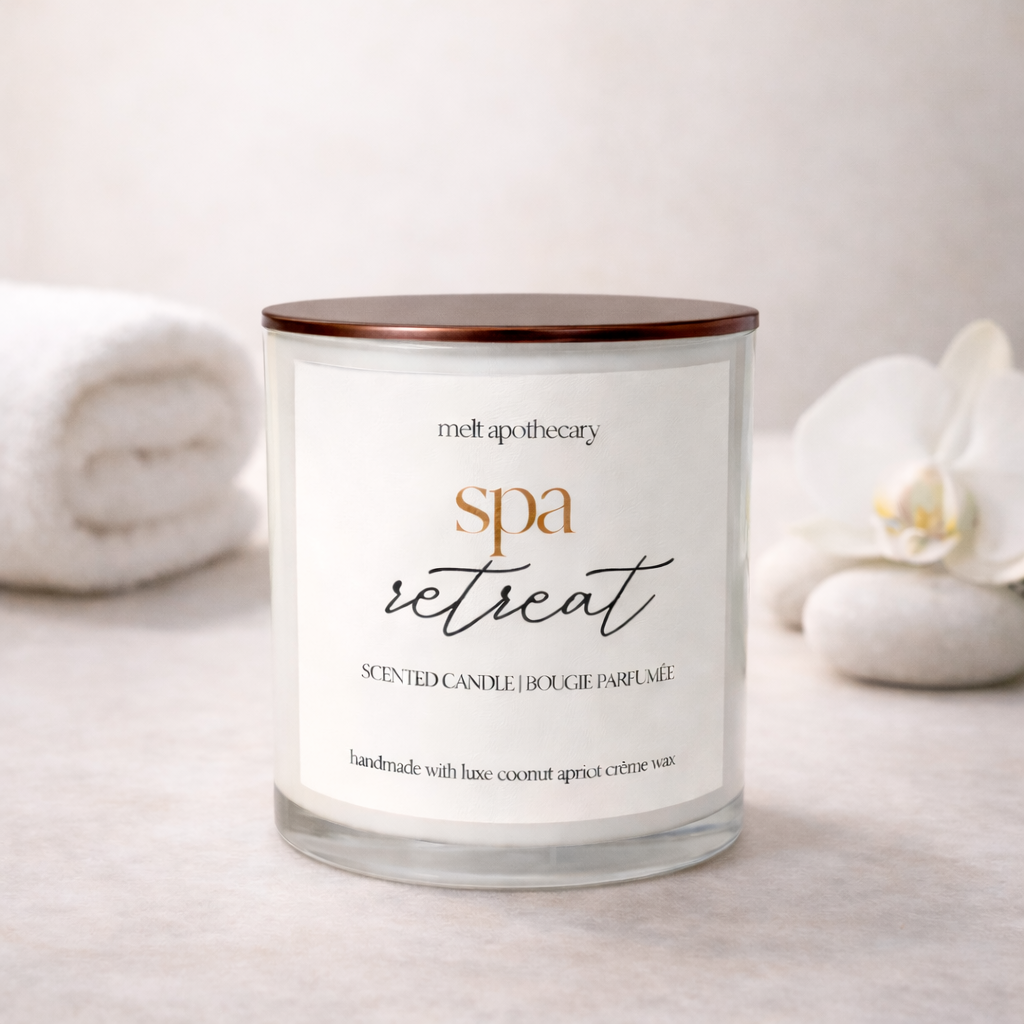 Candle labeled 'spa retreat' by Melt Apothecary with white flowers and stones in the background.