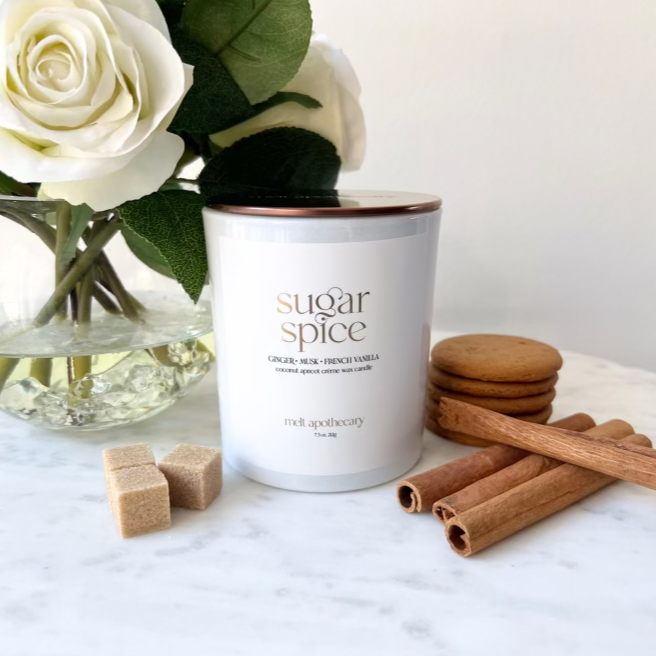 a 7.5 oz white sugar spice candle with white roses, cinnamon sticks, a ginger snap cookie and sugar cubes