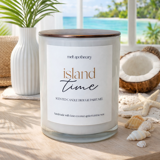 Candle labeled 'Island Time' on a table with a beach-themed background